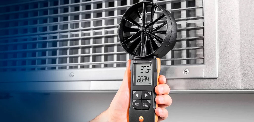 Especialista realizando medição de vazão e velocidade do fluxo de ar com anemômetro digital de hélice na grelha de climatização